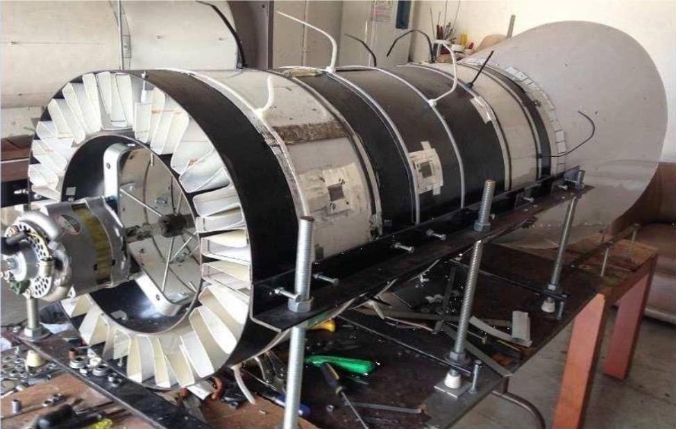 An early ATOM turbine prototype assembled on a workshop bench, its bladed rotor exposed at one end.