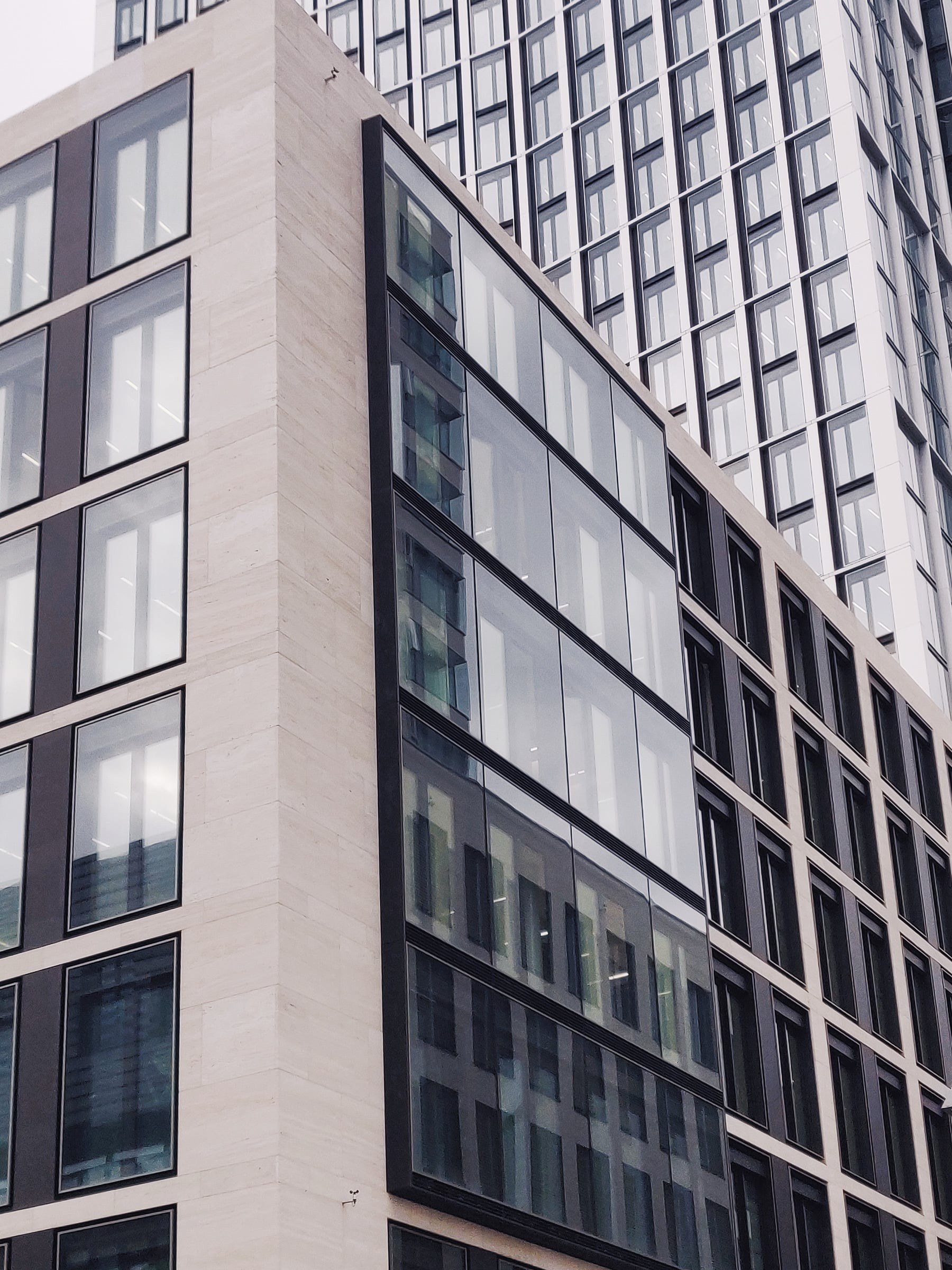 Stone and glass office facade rising above the street, seen from below.