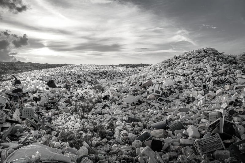 Black and white photograph of an open field strewn with discarded plastic waste.