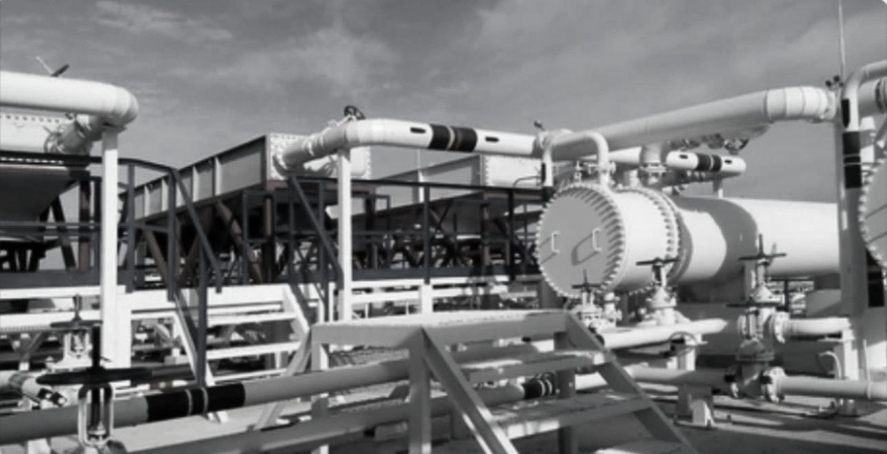 Black and white photograph of heat exchanger vessels and connecting pipework inside a processing plant.